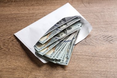 Tahta masanın üzerinde dolar banknotları olan zarf. Rüşvet kavramı