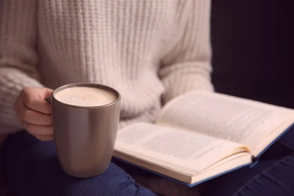 Kobieta z filiżanką kawy czyta książkę w domu, zbliżenie — Zdjęcie stockowe