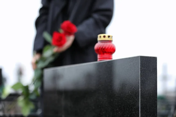 Frau mit roten Rosen im Freien, Fokus auf Kerze. Trauerfeier — Stockfoto