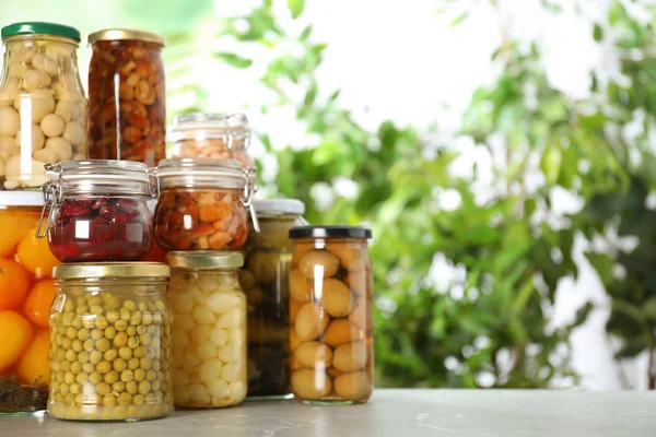 Glass jars of different pickled vegetables on marble table. Spac — Stock Photo, Image