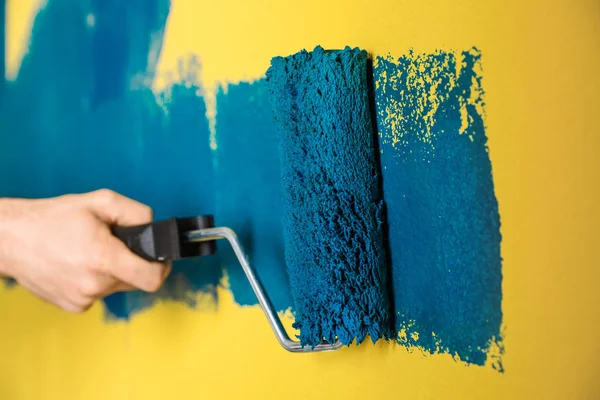 用蓝色染料粉刷黄色墙壁的人，特写 — 图库照片