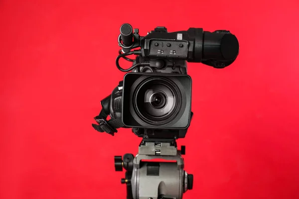 Modern professional video camera on red background