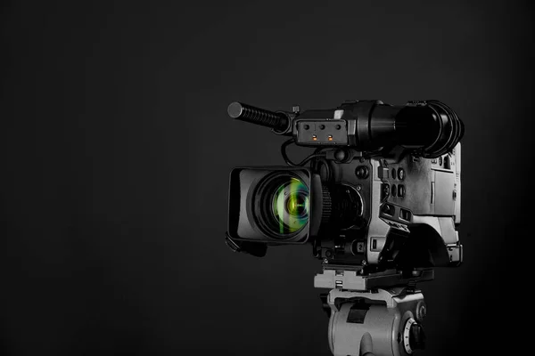 Modern professional video camera on black background. Space for text