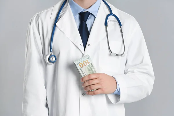 Dokter met omkoping op grijze achtergrond, close-up. Corruptie in de gezondheidszorg — Stockfoto