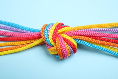 Açık mavi arka planda birbirine bağlanmış renkli ipler, üst manzara. Birlik kavramı