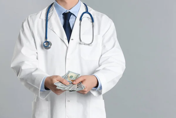 Dokter met omkoping op grijze achtergrond, close-up. Corruptie in de gezondheidszorg — Stockfoto