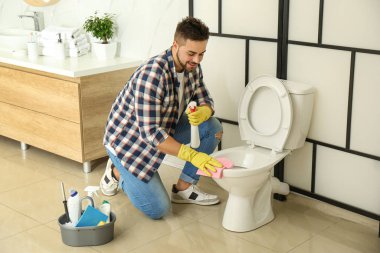 Genç adam tuvalette klozet temizliyor.