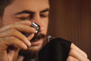 Jeweler working with ring on blurred background, closeup