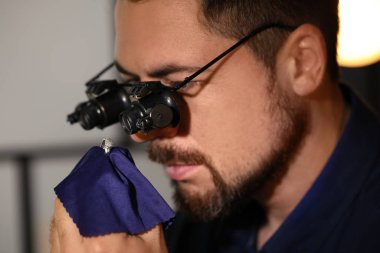 Jeweler working with ring on blurred background, closeup