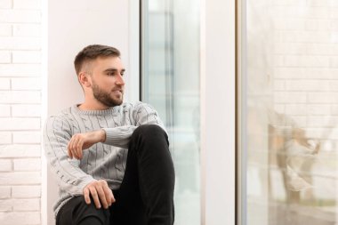 Evdeki pencerenin yanındaki yakışıklı genç adam.