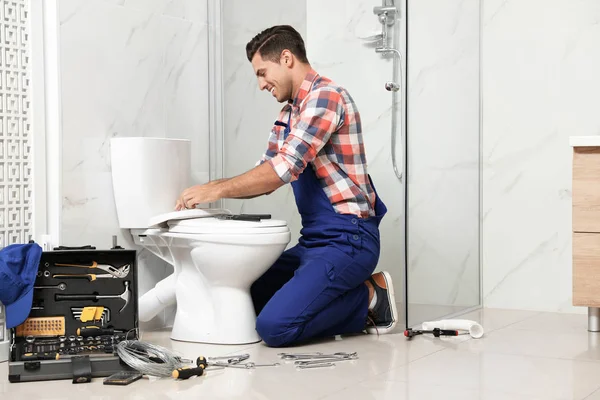 Professional plumber working with toilet bowl in bathroom — 스톡 사진