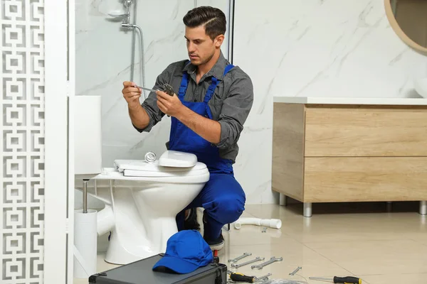 Professional plumber working with toilet bowl in bathroom — 스톡 사진