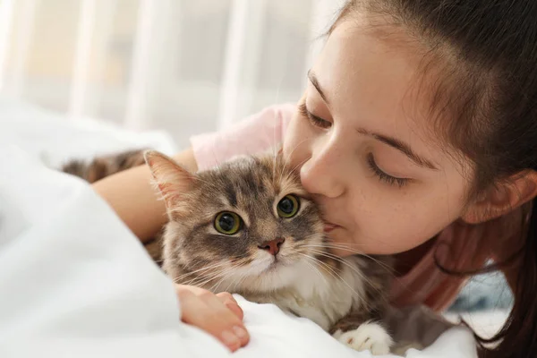 Leuk klein meisje met kat die thuis op bed ligt, close-up. Eerste blz. — Stockfoto