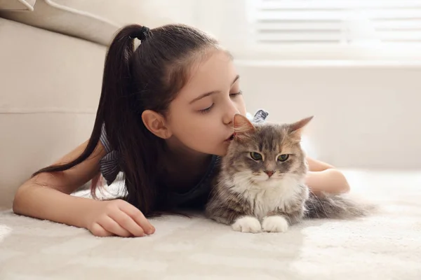 Ragazzina carina con gatto sdraiato sul tappeto a casa. Primo animale domestico — Foto Stock