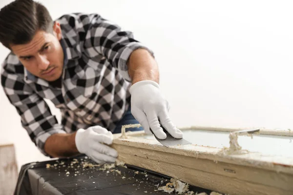 Man repareert oude beschadigde raam aan tafel binnen — Stockfoto