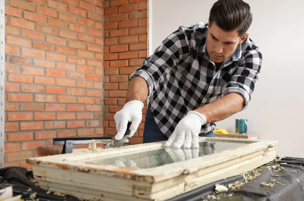 Man repareert oude beschadigde raam aan tafel binnen — Stockfoto