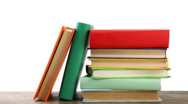 Beyaz arka plana karşı ahşap masadaki renkli kitap yığını