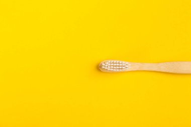 Sarı arka planda bambudan yapılmış diş fırçası, üst manzara. Boşluk 