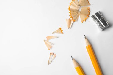 Beyaz arka planda grafit kalemler, talaşlar ve keskinleştirici, üst görünüm