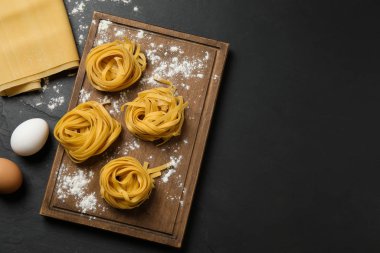Çiğ tagliatelle makarnası ve siyah masa üzerindeki ürünler. Spa