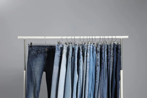 Scaffale con diversi jeans su sfondo grigio — Foto Stock