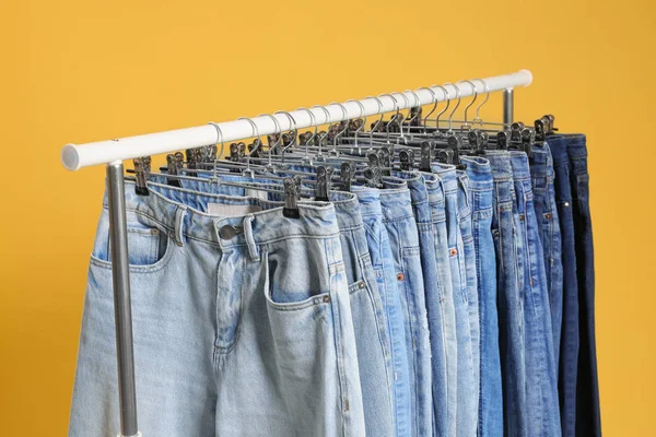 Cremalheira com jeans diferentes no fundo amarelo — Fotografia de Stock