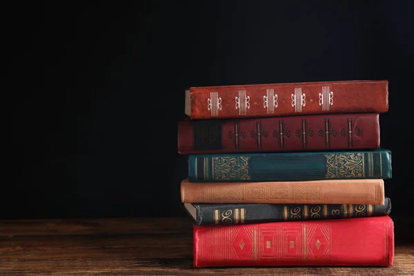 Gyűjteménye különböző könyvek fa asztalon ellen sötét backg — Stock Fotó