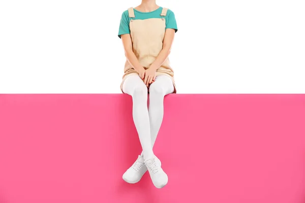 Mulher vestindo calças brancas e sapatos elegantes sentados na cor ba — Fotografia de Stock