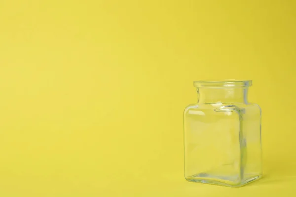 Frasco de vidro vazio aberto no fundo amarelo claro, espaço para texto — Fotografia de Stock
