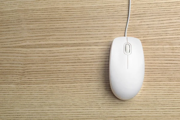 Wired computer mouse on wooden background, top view. Space for text