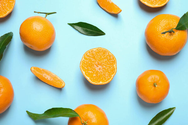 Flat lay composition with fresh ripe tangerines and leaves on light blue background. Citrus fruit