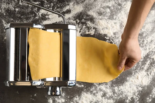 Woman preparing dough with pasta maker machine at grey table, to — 스톡 사진