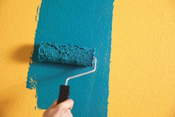 Man painting yellow wall with blue dye, closeup — Stock Photo, Image