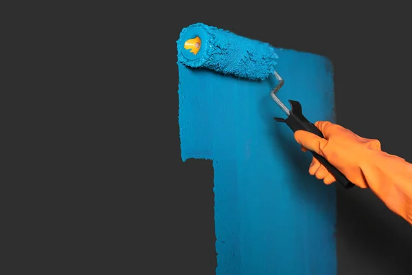 Žena maluje šedou stěnu s modrým barvivem, detailní záběr. Mezera pro text — Stock fotografie