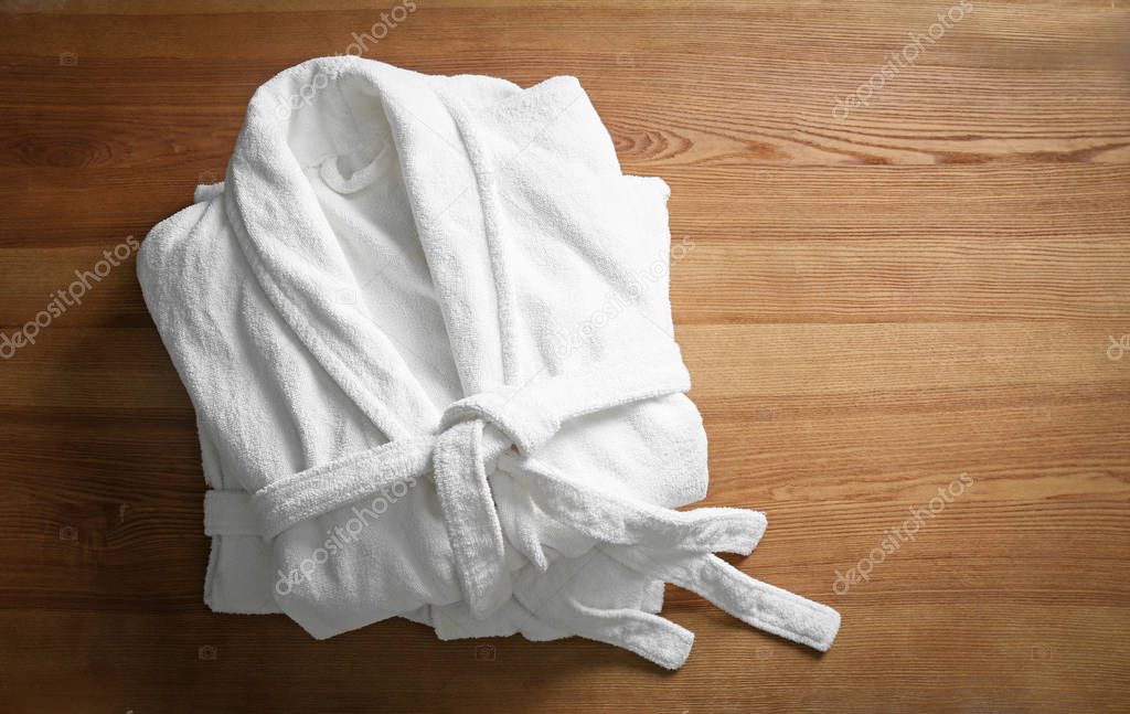 Clean folded bathrobes on wooden background, top view
