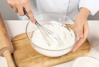 Ahşap masada yumurta beyazı çırpan kadın, yakın plan. Pasta yapmak.
