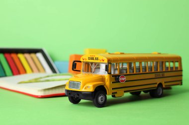 Okul otobüsü modeli ve yeşil arka planda kırtasiye malzemesi. f Taşı
