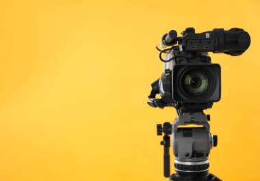 Sarı arka planda modern profesyonel video kamera. Metin için boşluk