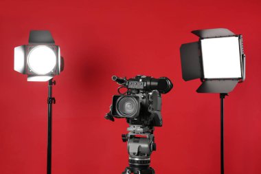 Kırmızı arkaplanda profesyonel video kamera ve ışıklandırma ekipmanları