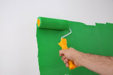 Yeşil boyalı beyaz duvarı boyayan adam, yakın plan. İç yenileme
