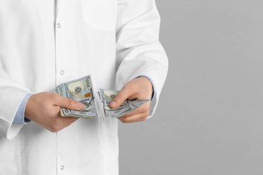 Gri arka planda rüşvet alan doktor, yakın plan. Yatakta yolsuzluk