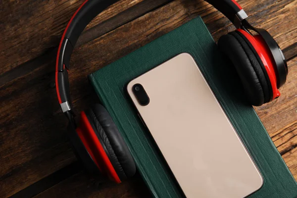 Libro, auriculares modernos y teléfono inteligente en la mesa de madera, primer plano —  Fotos de Stock