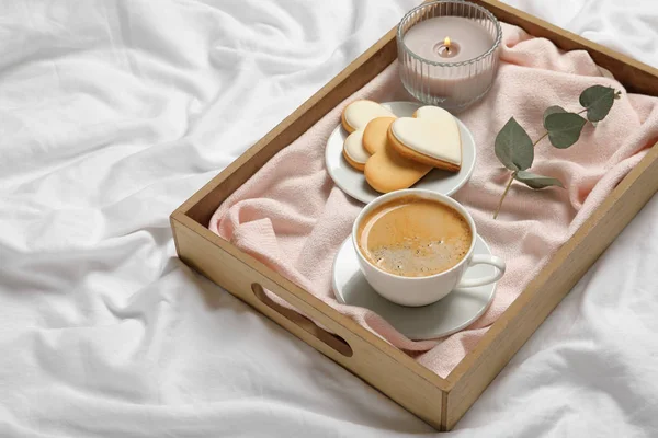 Wooden tray with coffee and cookies on bed. Romantic breakfast