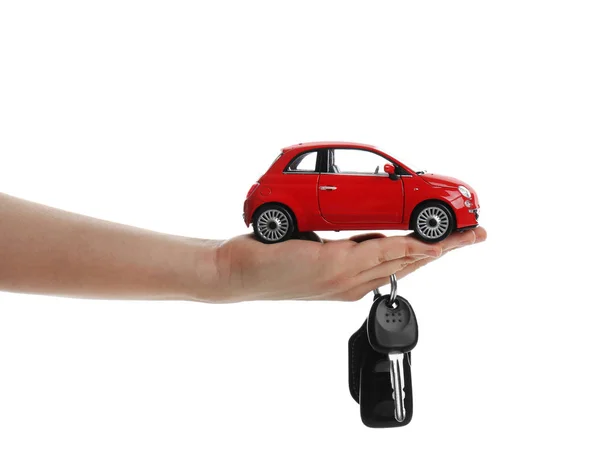 Mujer sosteniendo la llave y el modelo de automóvil en miniatura en blanco backgr —  Fotos de Stock
