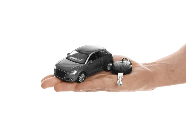 Muž drží klíč a miniaturní automobil model na bílém pozadí — Stock fotografie