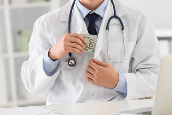 Doctor putting bribe into pocket in clinic, closeup. Corrupted m — Stock Photo, Image