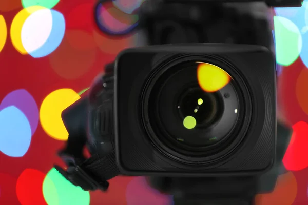Caméra vidéo moderne contre les lumières colorées floues, gros plan — Photo