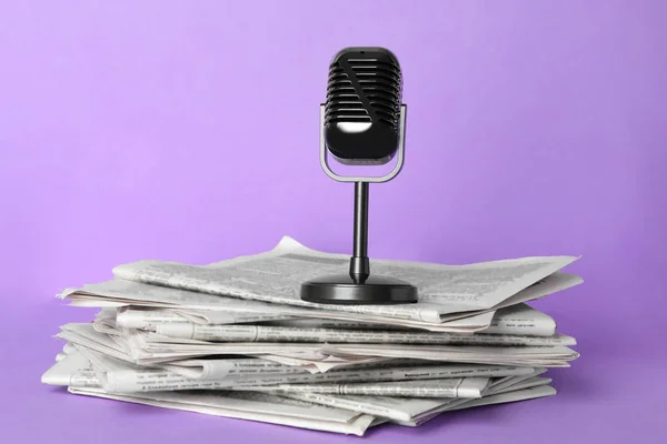 Gazety i zabytkowy mikrofon na jasnym fioletowym tle. Jo. — Zdjęcie stockowe
