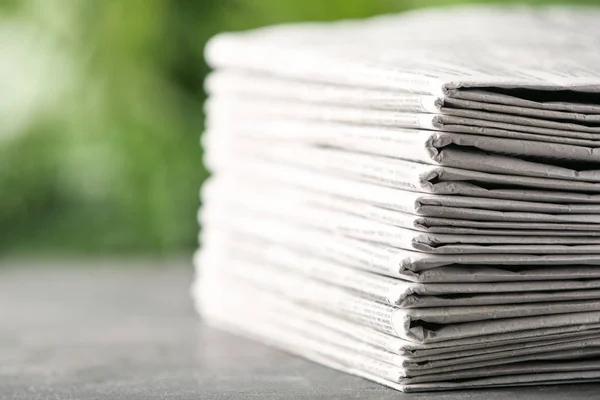 Gri Masadaki Gazeteler Bulanık Yeşil Arka Plana Karşı Yakın Plan — Stok fotoğraf