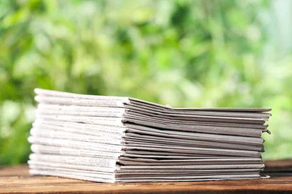 Tumpukan Surat Kabar Meja Kayu Dengan Latar Belakang Hijau Kabur — Stok Foto